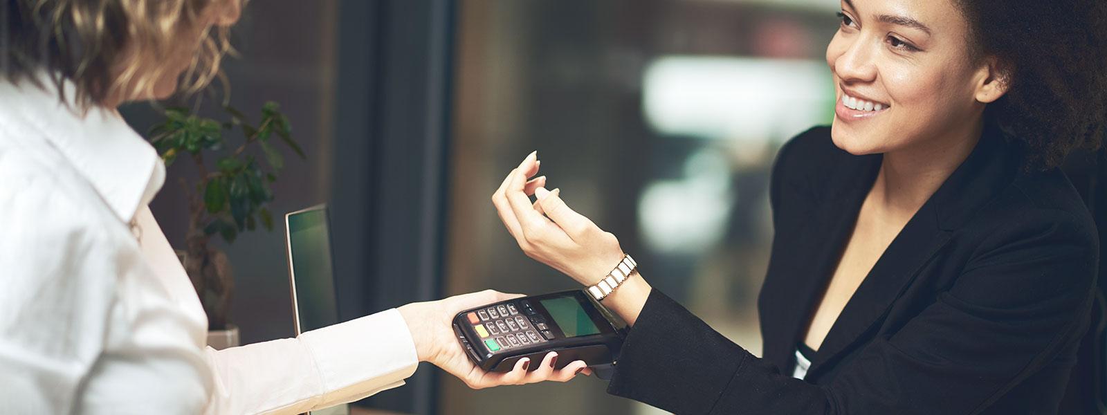 woman makes contactless payment with wearable payment technology (wristband) 